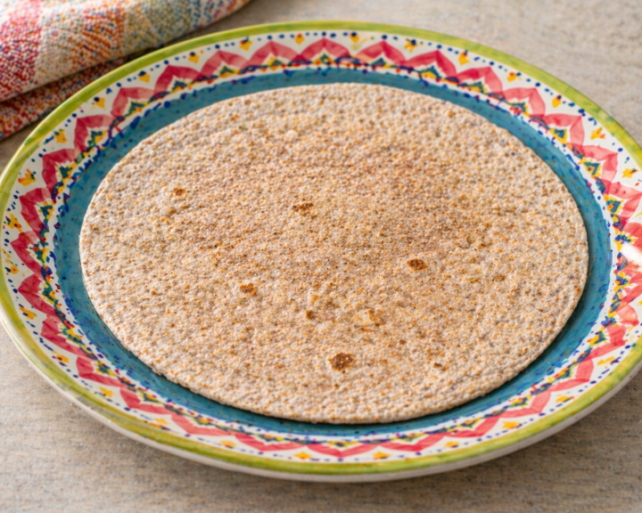Whole wheat tortilla on a colorful patterned plate.