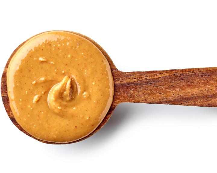 Creamy peanut butter in a wooden spoon.