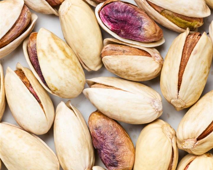 Pistachios, some shelled, on a flat surface