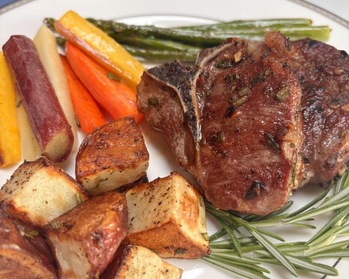 A plate with lamb chops, potatoes, and spring vegetables.