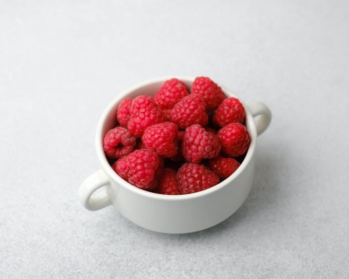 Fresh red raspberries in a white bowl.