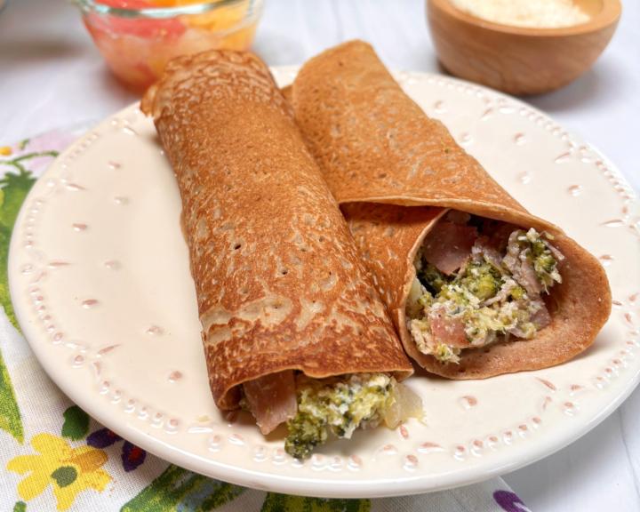  A plate of two savory crepes filled with vegetables.