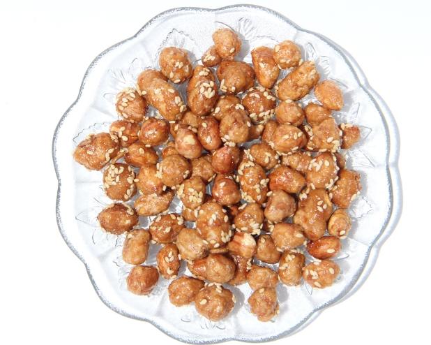 Spiced peanuts with sesame seeds on a clear glass plate.