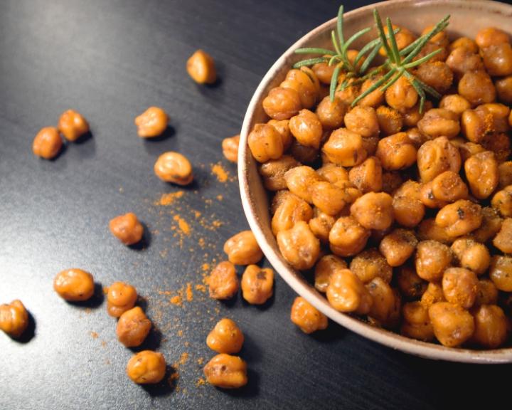 Roasted chickpeas in a bowl on a dark table.