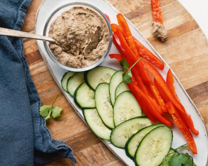 Snack platter with black bean dip, sliced cucumbers, and red bell peppers.