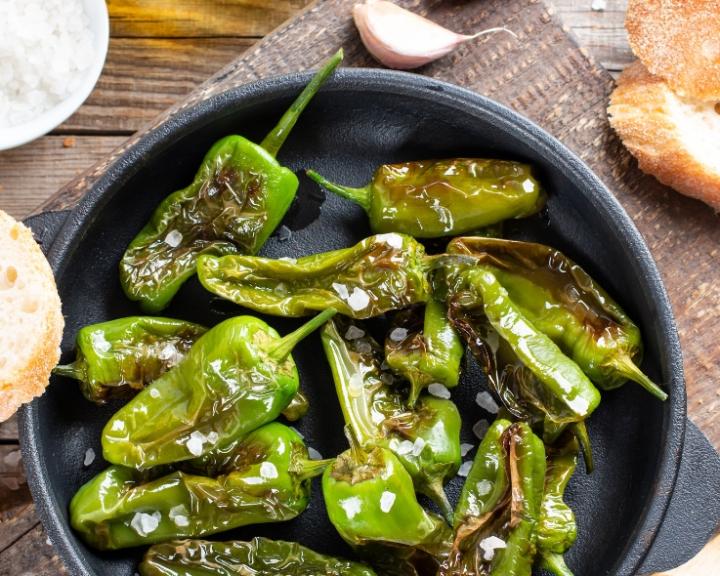 Blistered green peppers with sea salt in a black pan