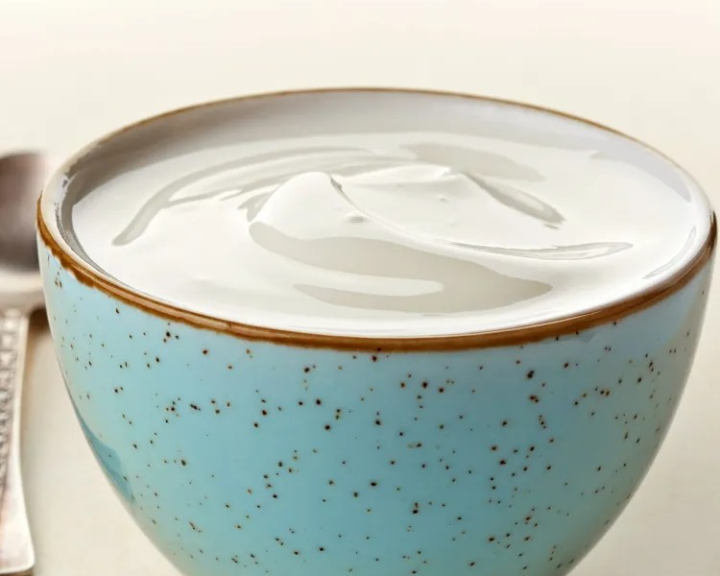 White yogurt in a speckled blue bowl with a spoon.