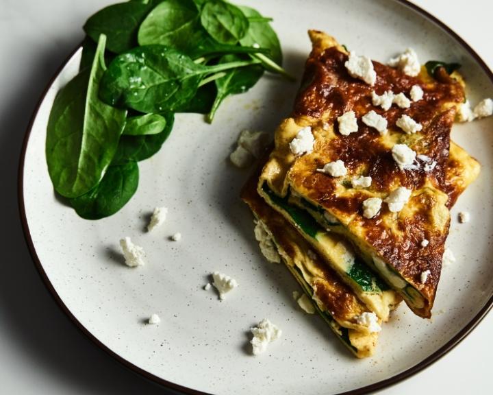 Spinach and feta omelet with fresh spinach on a white plate.