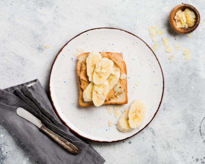 Peanut butter and banana toast on a white plate.