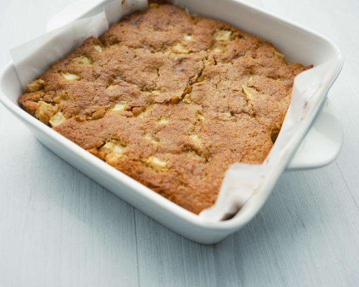 Golden-brown apple cake in a white baking dish.