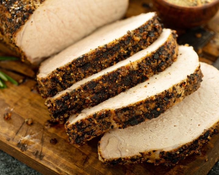 Sliced, seasoned pork loin on a cutting board