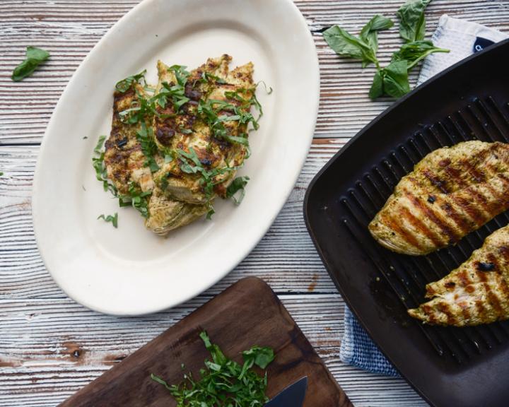 Healthy grilled chicken breasts with fresh herbs on a plate.