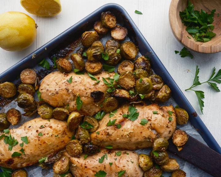 Roasted chicken breasts and Brussels sprouts on a sheet pan.