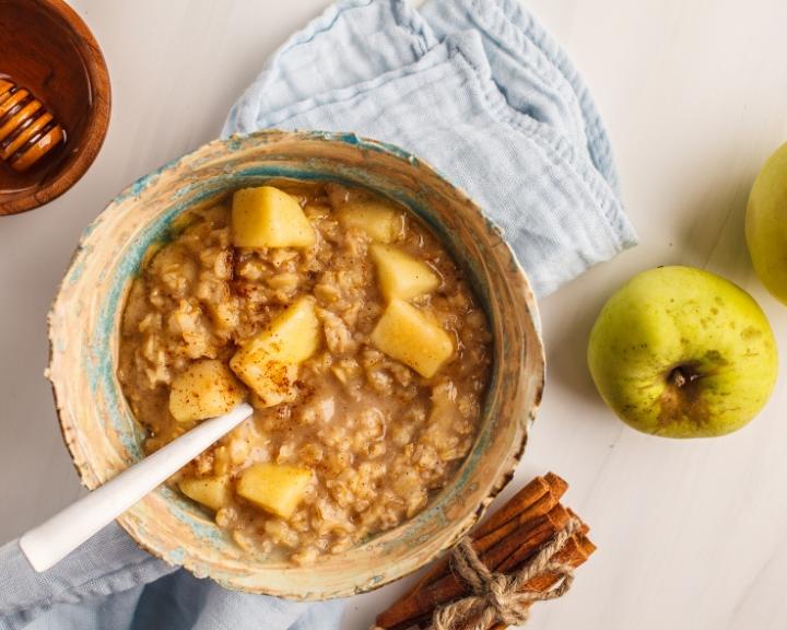 Warm apple cinnamon oatmeal in a bowl with a spoon.