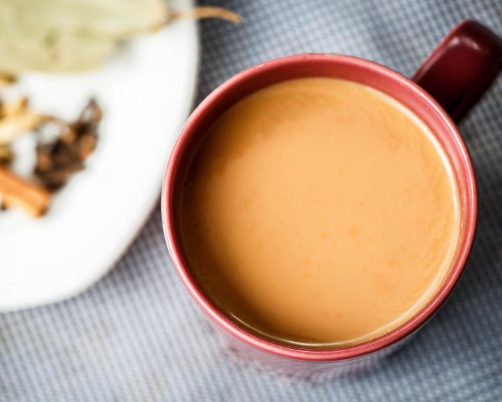 Chai tea in a red mug next to a plate of dried spices.